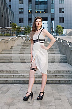 Young beautiful woman wearing trendy outfit, white dress and leather swordbelt. Longhaired brunette posing in the