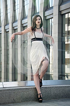 Young beautiful woman wearing trendy outfit, white dress and leather swordbelt. Longhaired brunette posing in the