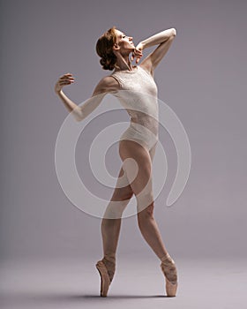 Young beautiful skinny ballerina is posing in studio