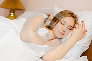 Young beautiful sleeping blonde lady lying in bed