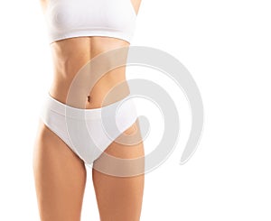 Young and beautiful slender girl in white swimsuit posing over white background. Healthcare, diet, sport and fitness