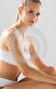 Young and beautiful slender girl in white swimsuit posing over white background. Healthcare, diet, sport and fitness