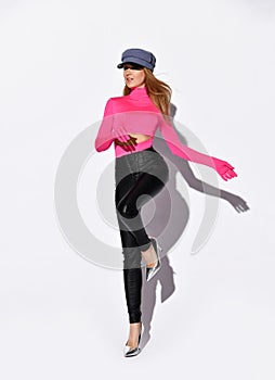 Young beautiful slim blond woman in pink longsleeve, trousers, shoes and cap posing