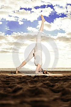 Young beautiful slim woman practices yoga on the beach at sunrise. Yoga at sunset