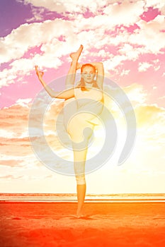 Young beautiful slim woman practices yoga on the beach at sunrise. Yoga at sunset