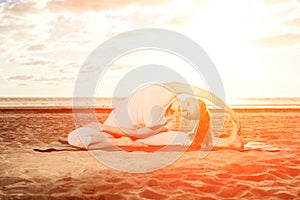 Young beautiful slim woman practices yoga on the beach at sunrise. Yoga at sunset