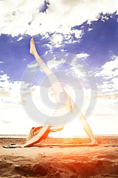 Young beautiful slim woman practices yoga on the beach at sunrise. Yoga at sunset