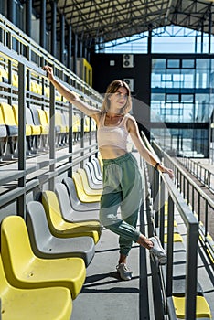 Young beautiful slim woman in sportswear relax near seats in the stadium. Lifestyle