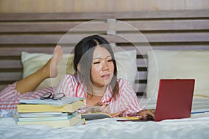 Young cute and happy nerdy Asian Korean student teenager girl in nerd glasses and hair ribbon studying at home bedroom sitting on