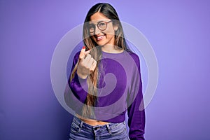 Young beautiful smart woman wearing glasses over purple isolated background Beckoning come here gesture with hand inviting