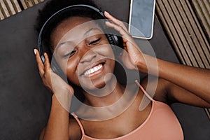 Young beautiful smiling african woman in headphones with closed eyes