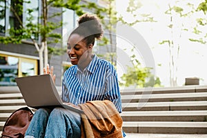 Young beautiful smiling african woman holding video conference with laptop