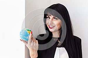 Young Beautiful smiling brunette woman dressed in black business suit holding a globe of the planet Earth. Travel concept