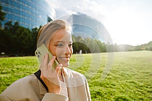 Young beautiful smiling business woman talking phone and looking aside