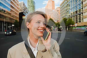 Young beautiful smiling business woman talking phone and looking aside