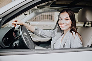 Young beautiful smiling girl driving a car in the street