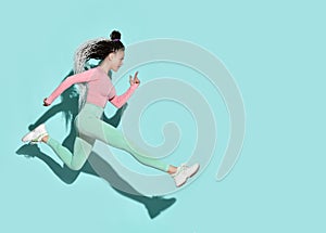 Young beautiful smiling girl with modern hairstyle in sportswear and sneakers jumping running with legs stretched out