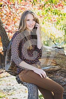 Young beautiful smiling girl talking on mobile phone in park