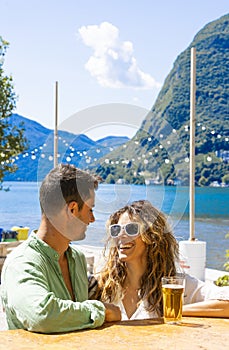 Young beautiful smiling girl with white teeth jokes with her friend. In the background the lake and the San Salvatore mountain in