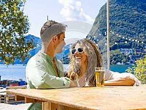 Young beautiful smiling girl with white teeth jokes with her friend. In the background the lake and the San Salvatore mountain in