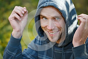 Young beautiful smiling man in sports wear and hood on head with