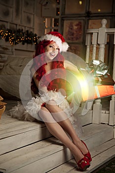 Young beautiful smiling santa woman. Christmas Fashionable luxury girl celebrating New Year holding gift
