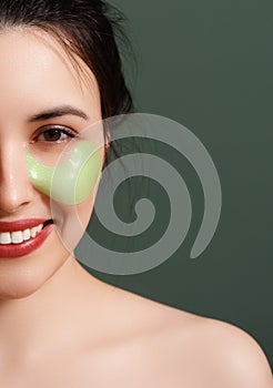 A young beautiful smiling woman with cosmetic patches on her eyes. Cosmetic procedures skin care around the