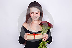 Young beautiful smiling woman with flowers and gift. Dating, rel