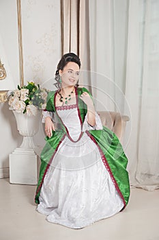 Young beautiful smiling woman in green rococo style medieval dress