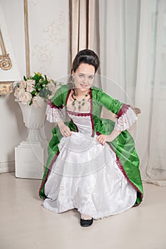 Young beautiful smiling woman in green rococo style medieval dress