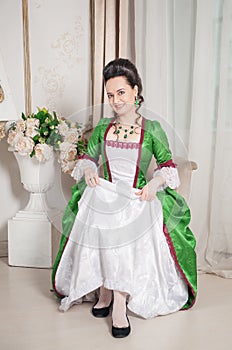 Young beautiful smiling woman in green rococo style medieval dress