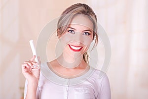 Young beautiful smiling woman holding a menstruation cotton tampon in her hand