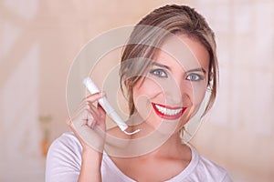 Young beautiful smiling woman holding a menstruation cotton tampon in her hand, in a blurred background