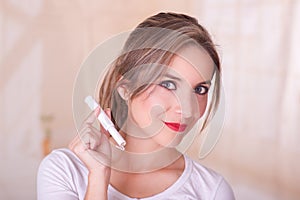 Young beautiful smiling woman holding a menstruation cotton tampon in her hand, in a blurred background