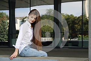 Young beautiful smiling woman with long straight hair looked down