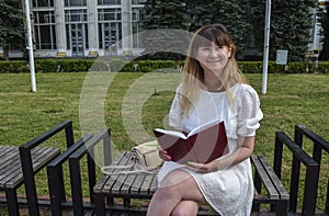 Young beautiful smiling woman looking in camera with notepad in park