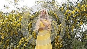 Young beautiful smiling woman in spring Australian Golden wattle trees.