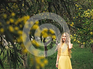 Young beautiful smiling woman in spring Australian Golden wattle trees.