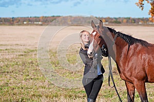 Young beautiful smiling woman walking with horse