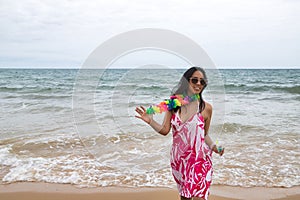 Young and beautiful South American woman, brunette, with sunglasses, bikini and flower necklace with a glass of blue wine in her