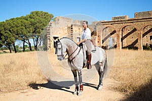 Young and beautiful Spanish woman on a Thoroughbred horse for competition. The woman has gone out to prepare the horse for