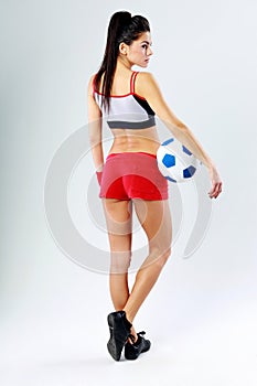 Young beautiful sport woman standing with soccer ball