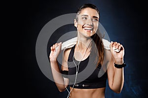 Young beautiful sportive girl listening music over dark background.