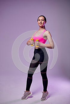 Young beautiful sports girl in leggings and a top does exercises with dumbbells. Healthy lifestyle. A woman goes in for sports at