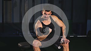 Young and beautiful sportsman athlete bodybuilder man doing exercises for the muscles of the hands of dumbbells in the