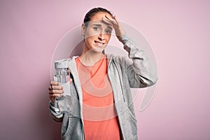 Young beautiful sporty woman doing sport drinking bottle with water to refreshment stressed with hand on head, shocked with shame