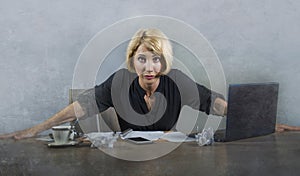 Young beautiful stressed and upset blonde woman working with laptop computer feeling tired overwhelmed by paperwork looking angry