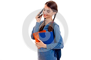 Young beautiful student girl with backpack posing and talks phone isolated on white background in studio