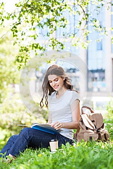 Young beautiful student girl reading a book in a city park or university campus. Education and university lifestyle concept