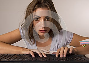 Young beautiful student girl or working woman typing on computer keyboard looking focused and concentrated in hard work